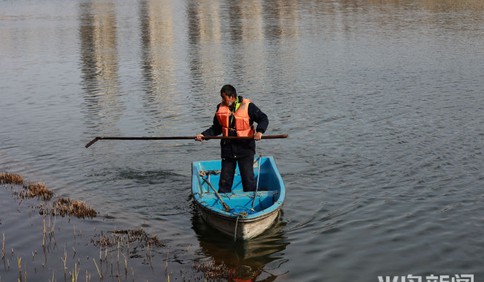 青岛国信工人们划小船清洁人工湖 同时提醒游客不要乱扔垃圾