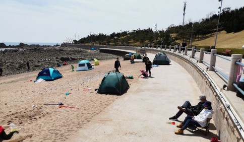 青岛前海一线不少市民在沙滩上撑起帐篷沐浴阳光