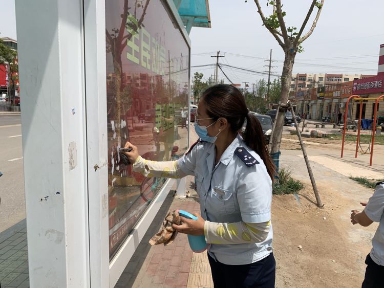 等车城阳巴士120路乘务员清理公交站台小广告 保持干净整洁等车环境