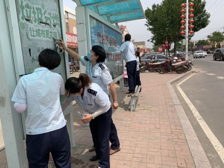 等车城阳巴士120路乘务员清理公交站台小广告 保持干净整洁等车环境