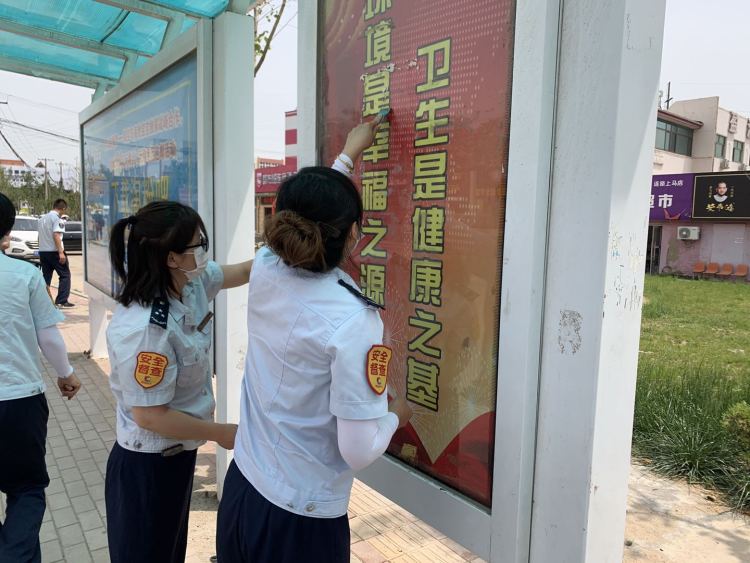 等车城阳巴士120路乘务员清理公交站台小广告 保持干净整洁等车环境