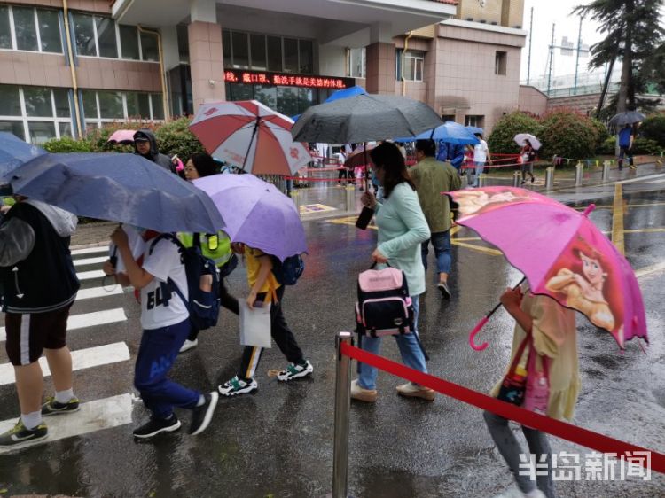 雨中青岛：孩子和家长在雨中赶往学校 下雨天出行请注意安全