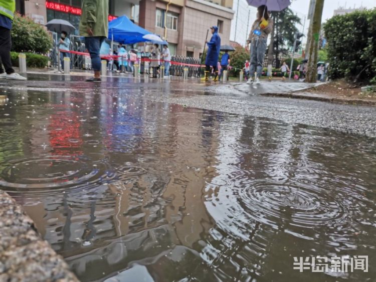 雨中青岛：孩子和家长在雨中赶往学校 下雨天出行请注意安全