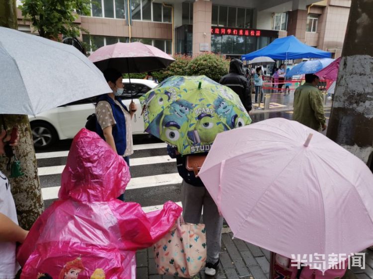 雨中青岛：孩子和家长在雨中赶往学校 下雨天出行请注意安全