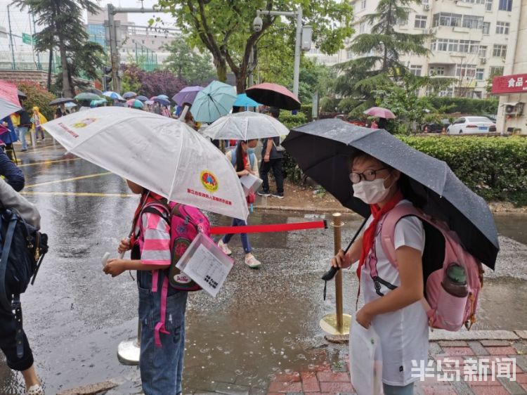 雨中青岛：孩子和家长在雨中赶往学校 下雨天出行请注意安全