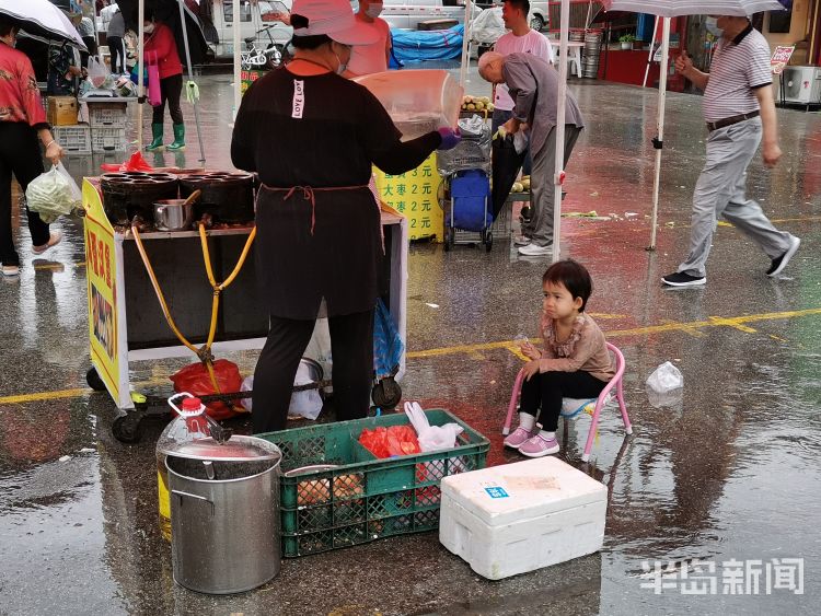 雨中青岛新田路一侧早市上 不少摊主雨中坚守