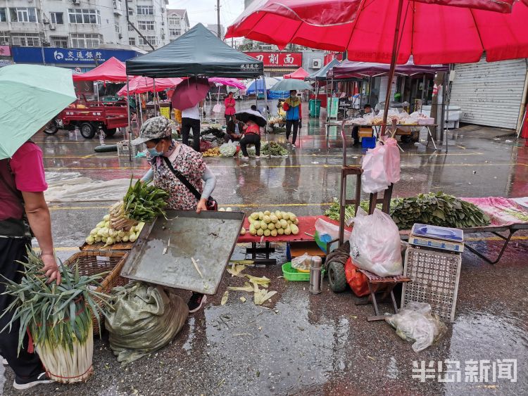 雨中青岛新田路一侧早市上 不少摊主雨中坚守