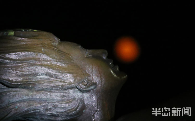 红月红色满月与雕塑园时尚雕塑相映成景 吸引路人驻足观看