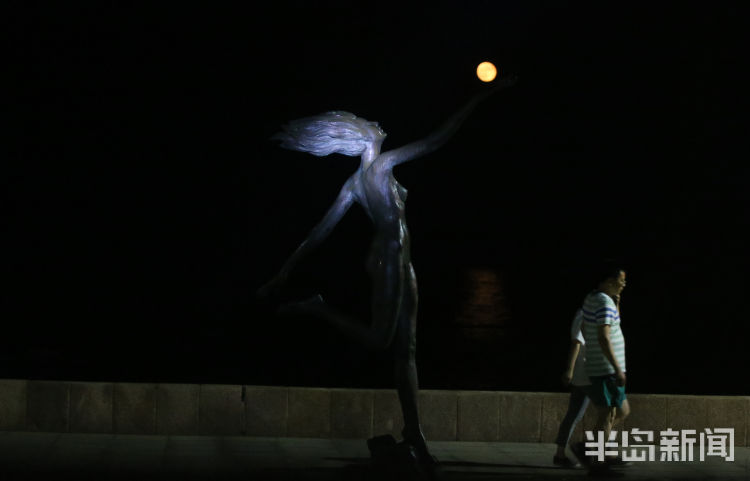 红月红色满月与雕塑园时尚雕塑相映成景 吸引路人驻足观看