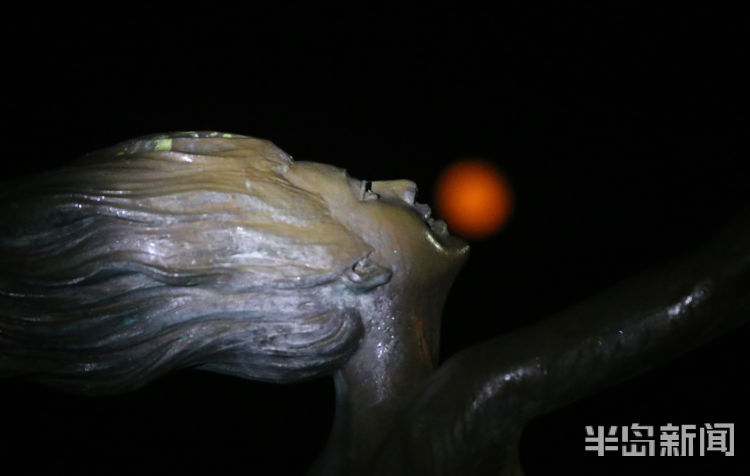 红月红色满月与雕塑园时尚雕塑相映成景 吸引路人驻足观看