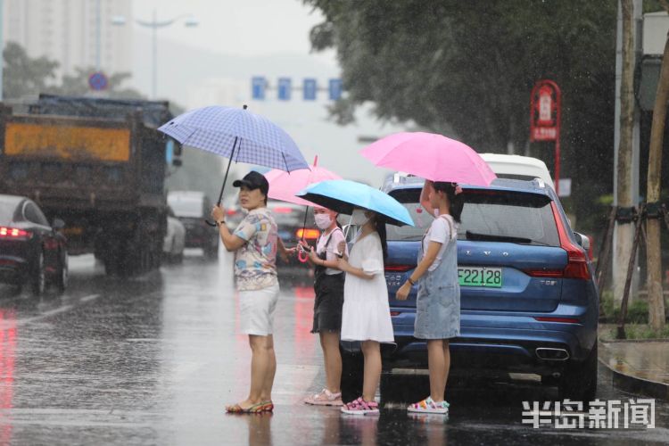 急雨突袭青岛市区 路上行人风雨中疾步行走