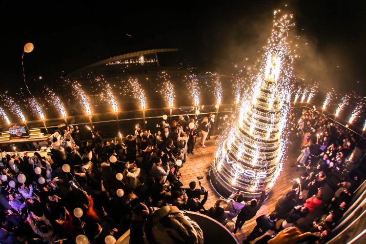 许多年轻人聚集在海尔洲际一酒吧天台上,背靠奥帆夜色点燃冷焰火许下